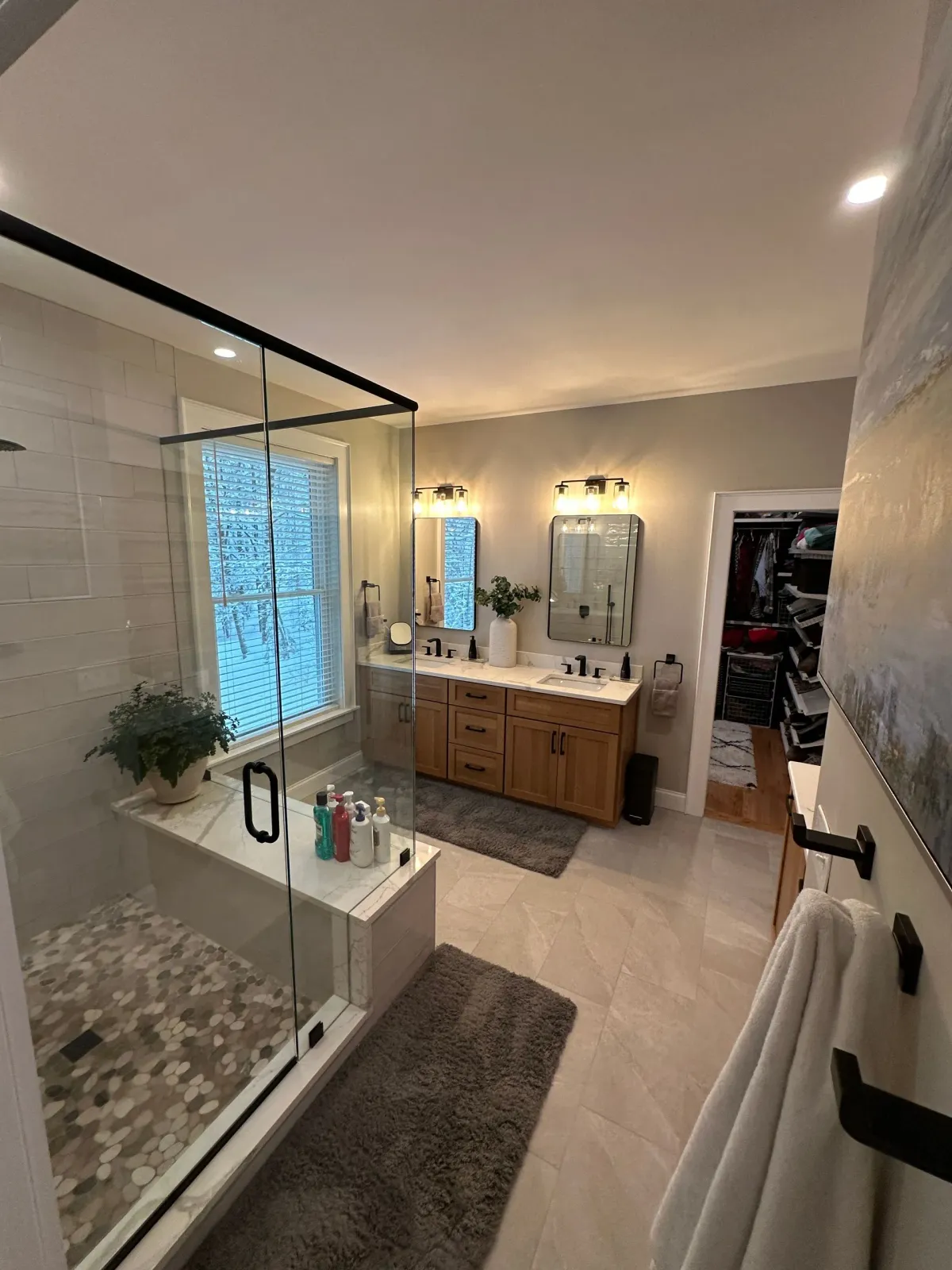 Modern bathroom with glass shower, freestanding tub, and wooden vanity with mirror lights.