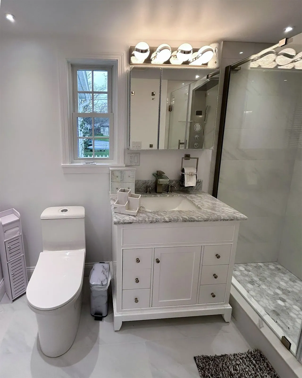 Bathroom with white vanity, toilet, and a window. Includes shower and decorative Star Wars helmets.