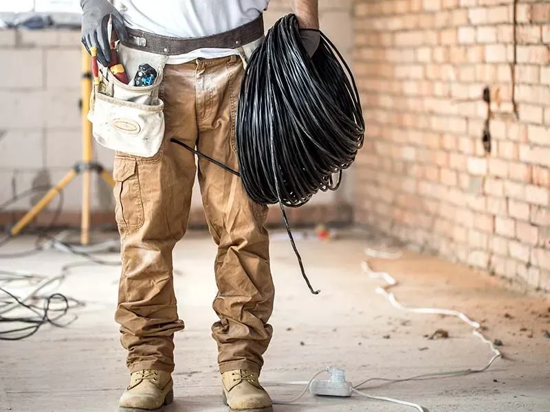 A man is holding a roll of wire in a room.