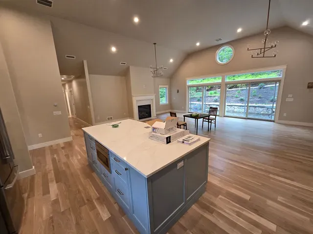 Spacious modern kitchen and dining area with island, wood floors, and large sliding glass doors.