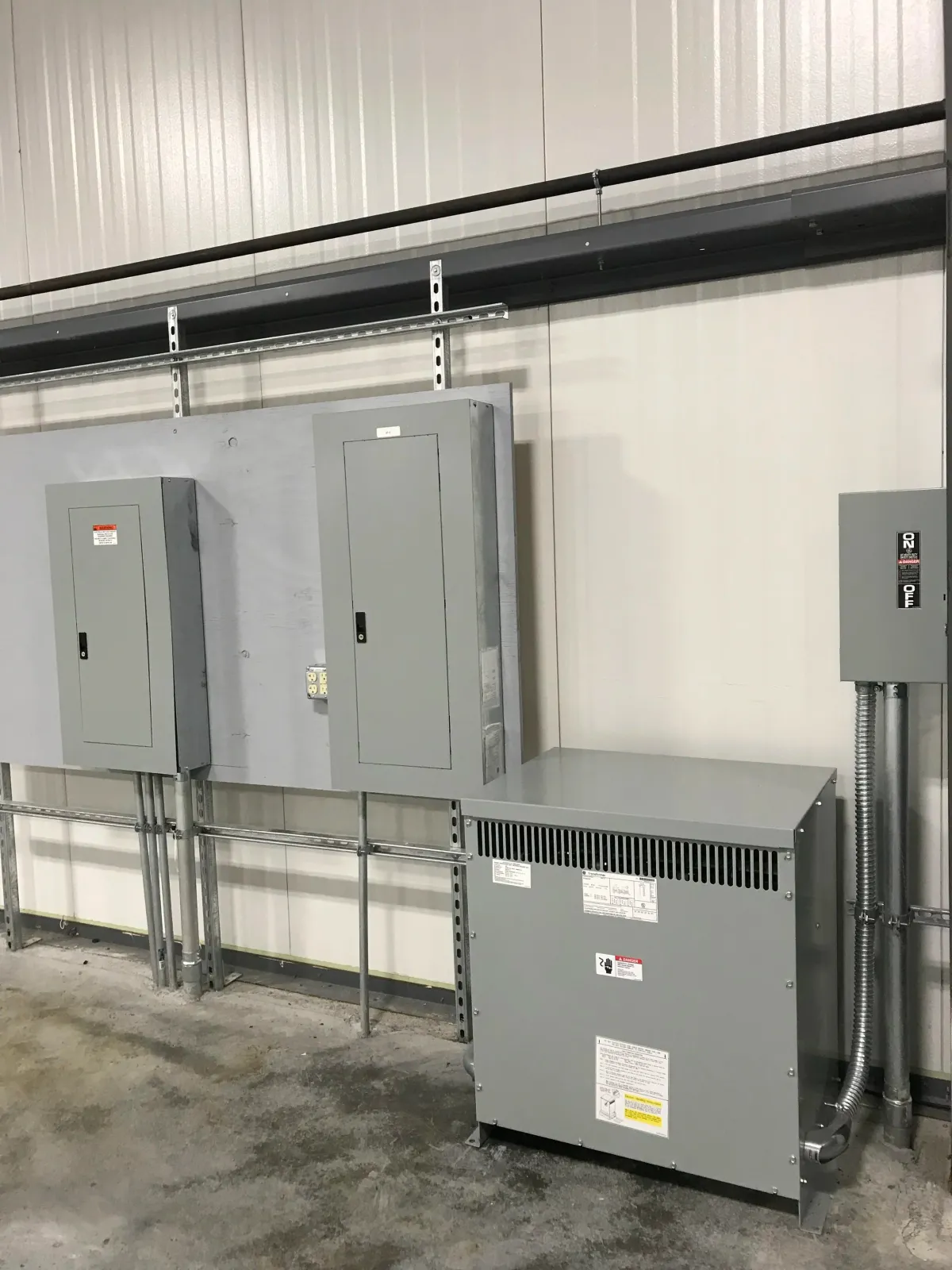 Electrical panels and equipment mounted on a white wall in an industrial setting.