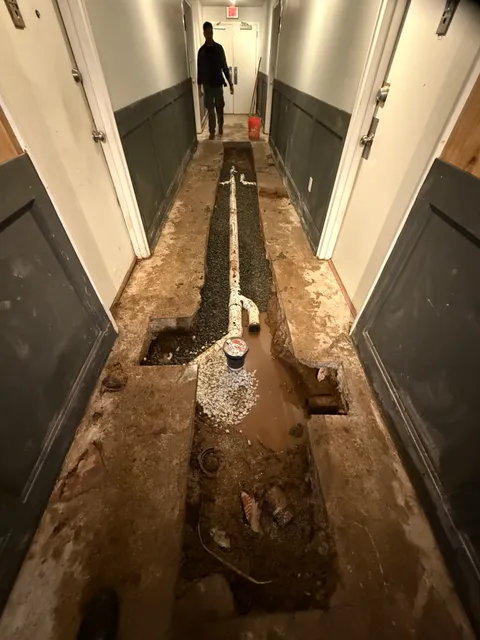 New Schedule 40 PVC drain line installed, bedded in gravel, and ready for inspection before the slab is patched and the hallway is restored.