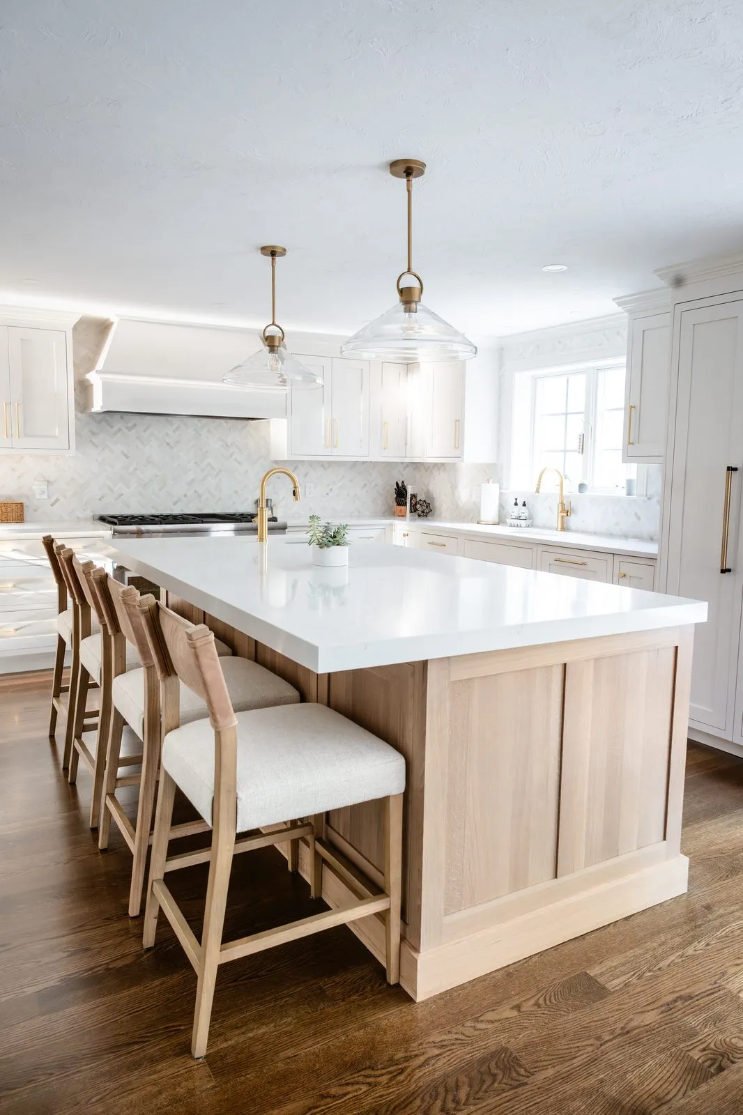 Rosewood Court kitchen with white oak island, glass pendant lights with brass fittings, and all-white cabinetry