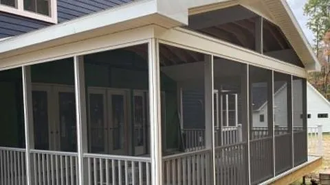 Finished screened porch with a gable roof and railings on the back of a navy house