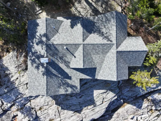 Aerial view of a house with a patterned roof on rocky terrain