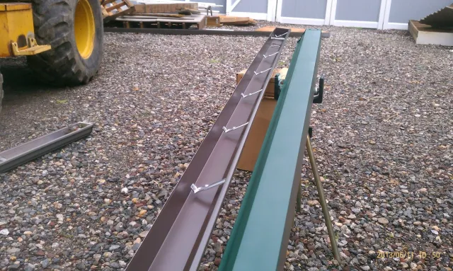 A green and brown piece of metal is sitting on a gravel ground