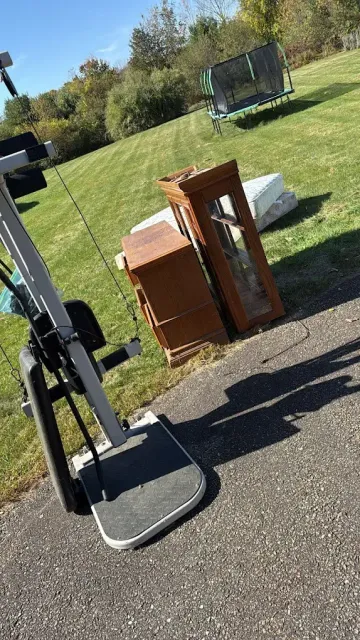 Cabinet, dresser and exercise equipment set out on a driveway for removal