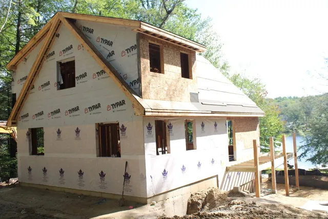 A house is being built next to a body of water.