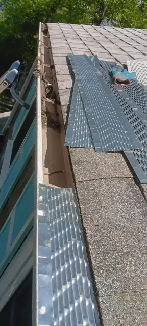 Roof under repair with gray shingles and metal flashing, viewed along the roof edge.