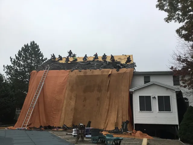 Crew removing previous roof shingles