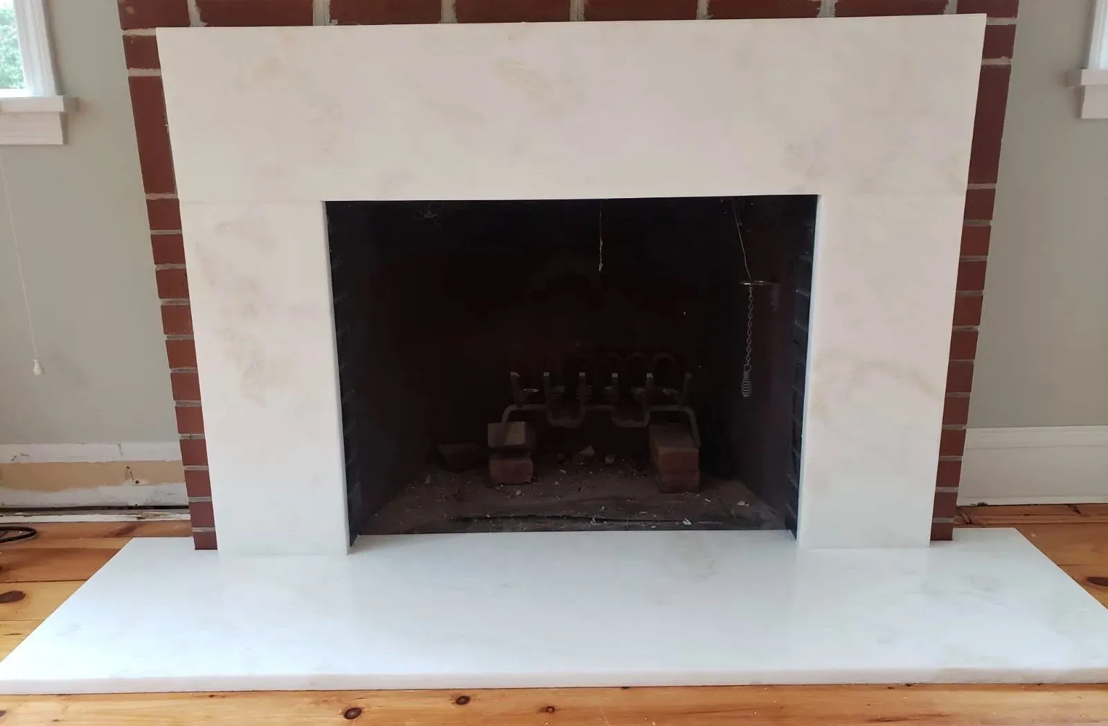 Fireplace with white marble surround and hearth, set against a brick and neutral wall interior.