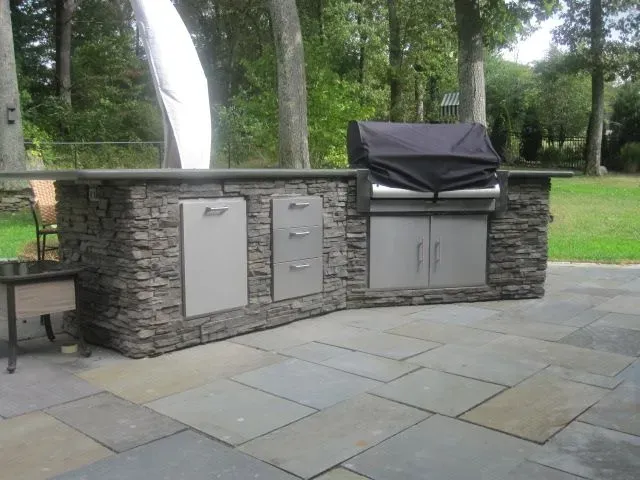 An outdoor kitchen with a grill and a black cover