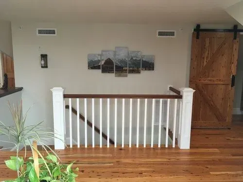 A wooden staircase with a white railing and a wooden barn door.