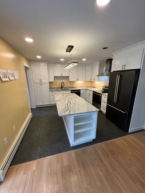 Kitchen after remodel with bright cabinets, island, and new flooring