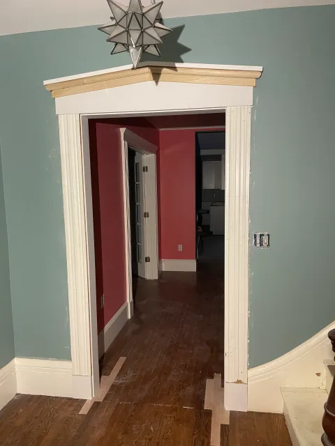 A hallway with pink walls and a white door with a star on top of it.