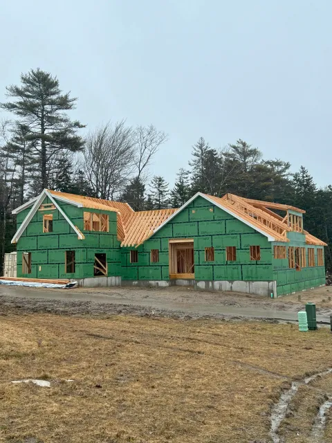 Wide view of a large residential home framing project wrapped in green ZIP System weather barrier sheathing.