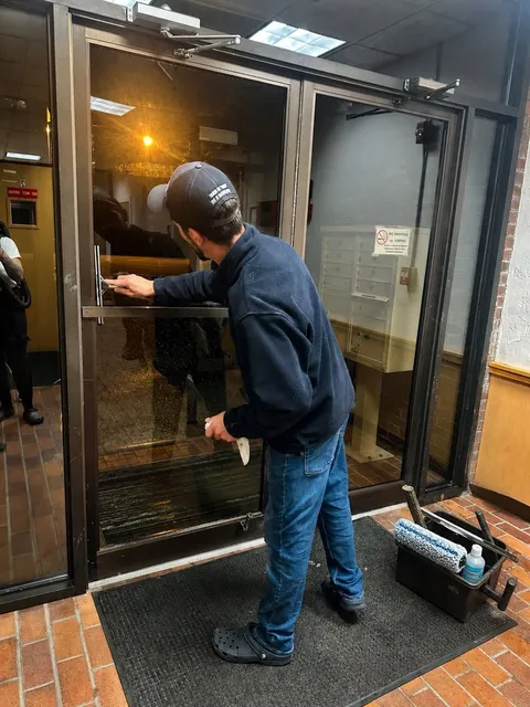 A team member cleaning the glass entrance doors of a commercial building