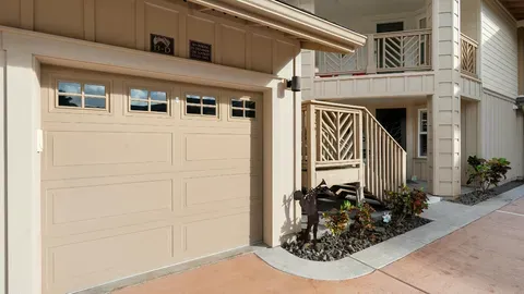 Beige garage door on a tan house with a balcony and walkway.