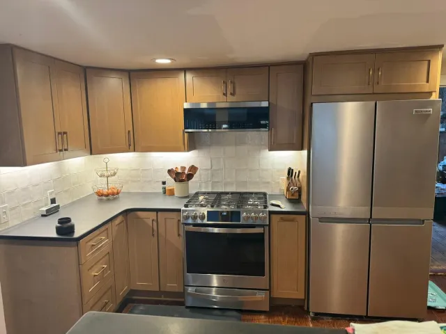Light brown wood kitchen cabinets with stainless steel refrigerator