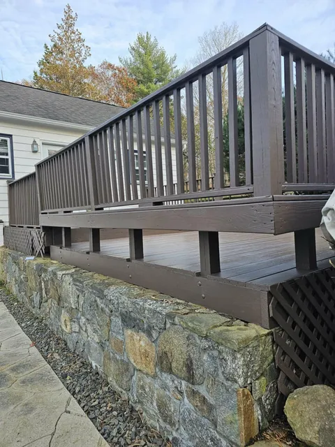 Stained deck railing above a fieldstone retaining wall