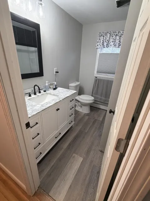 Finished bathroom remodel with marble-top vanity, new flooring and fixtures