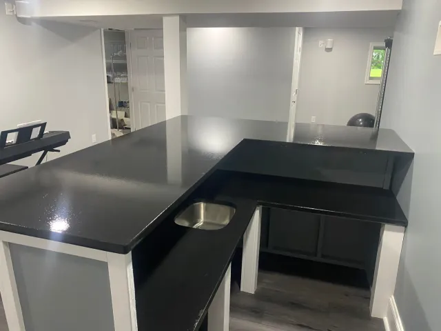 A kitchen with a black counter top and a sink.