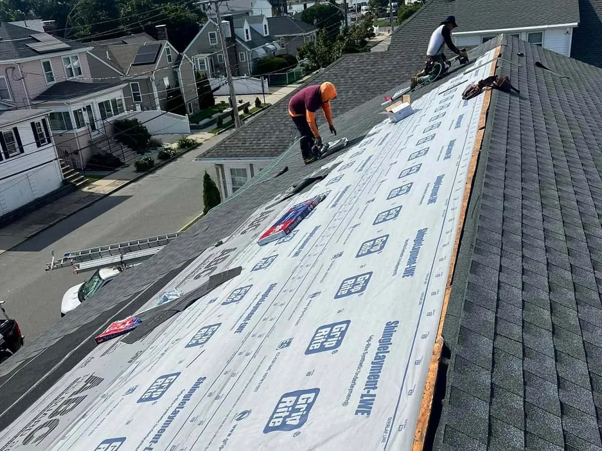 Crew laying underlayment during a roof repair