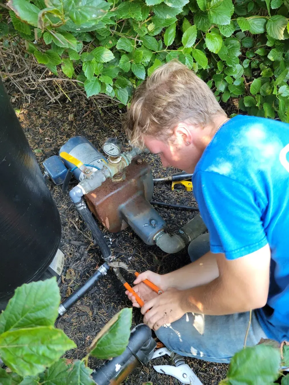 A man in a blue shirt is working on a pipe