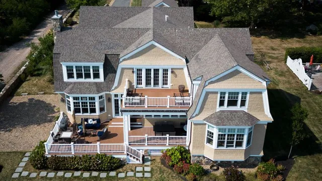 Aerial view of a home with beige exterior and white trim and fencing and large deck