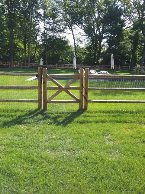 A wooden fence is along the side of a road next to a house.