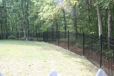 Installed black ornamental aluminum fence along a wooded yard