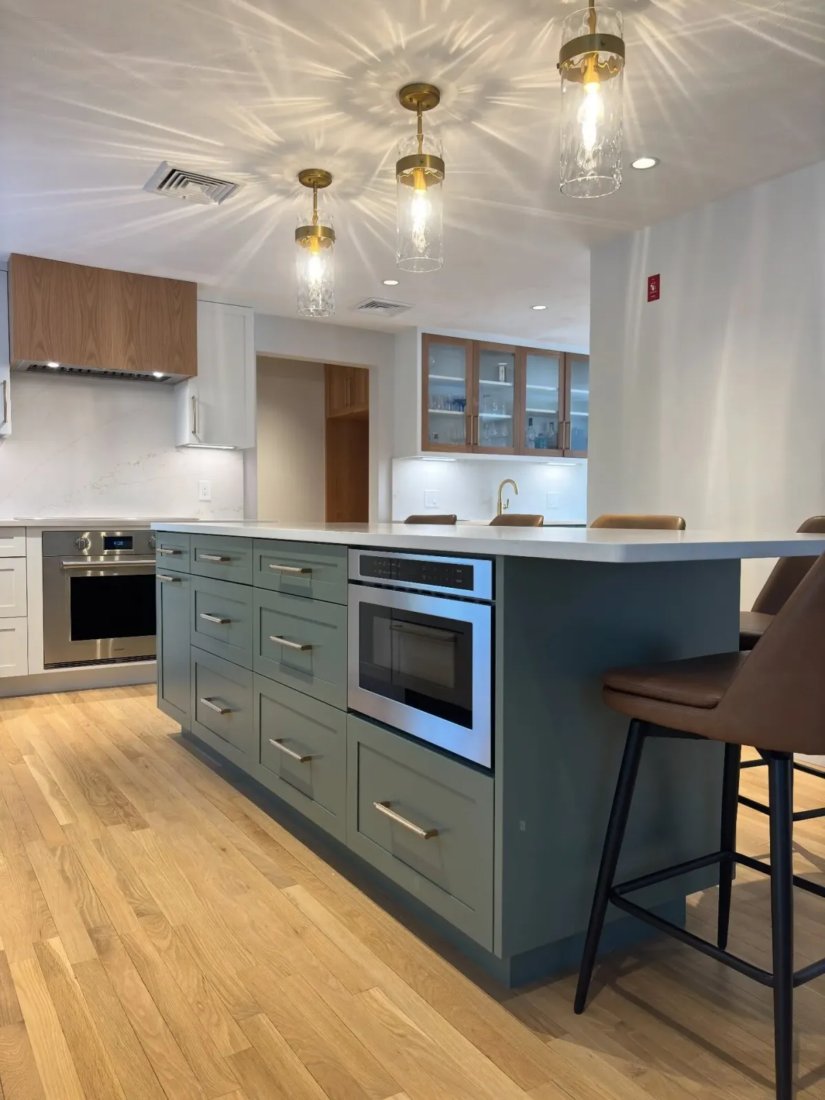 Not just another "millennial grey" kitchen.

Layering warmth - off-white cabinetry across the perimeter, white oak wrapping the hood &amp; pantry, and sage green anchoring the island &amp; wine bar.

A color and material palette like this b