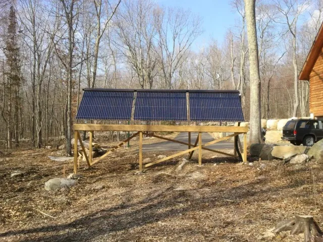 A row of solar panels are sitting on top of a wooden structure in the woods.