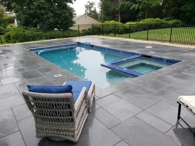 A chair is sitting next to a large swimming pool.