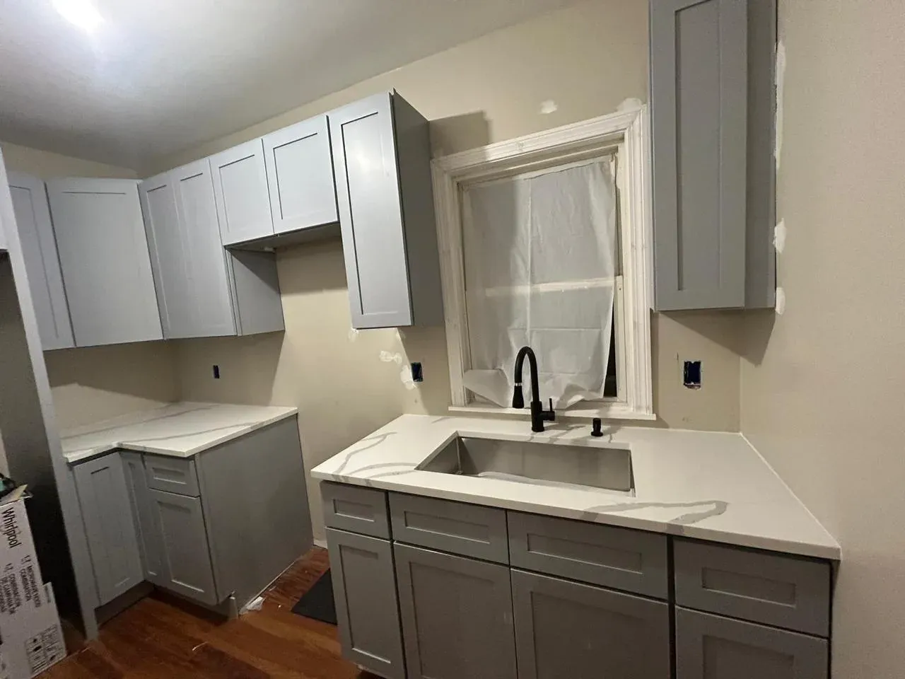 Close-up of a Calacatta Cosmos kitchen installation featuring a stainless steel sink and matte black hardware.