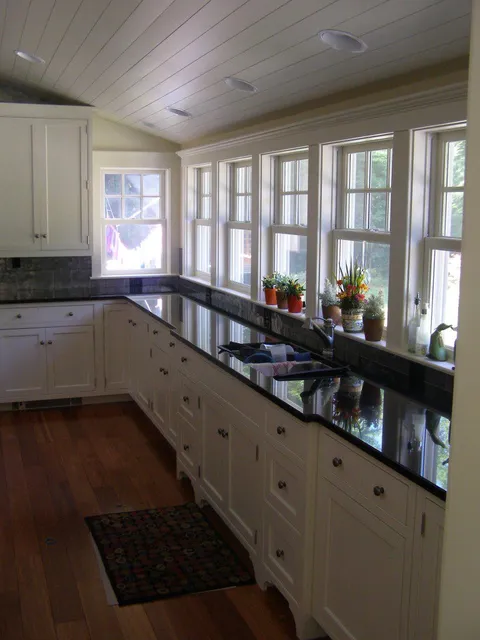 A kitchen with white cabinets and black counter tops.