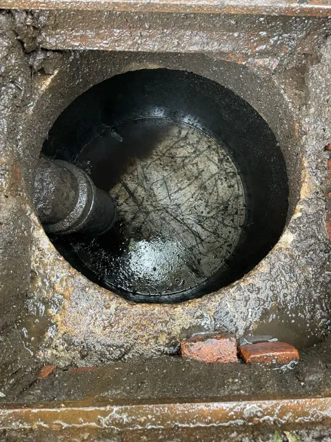 A close up of a hole in a drain with water coming out of it.