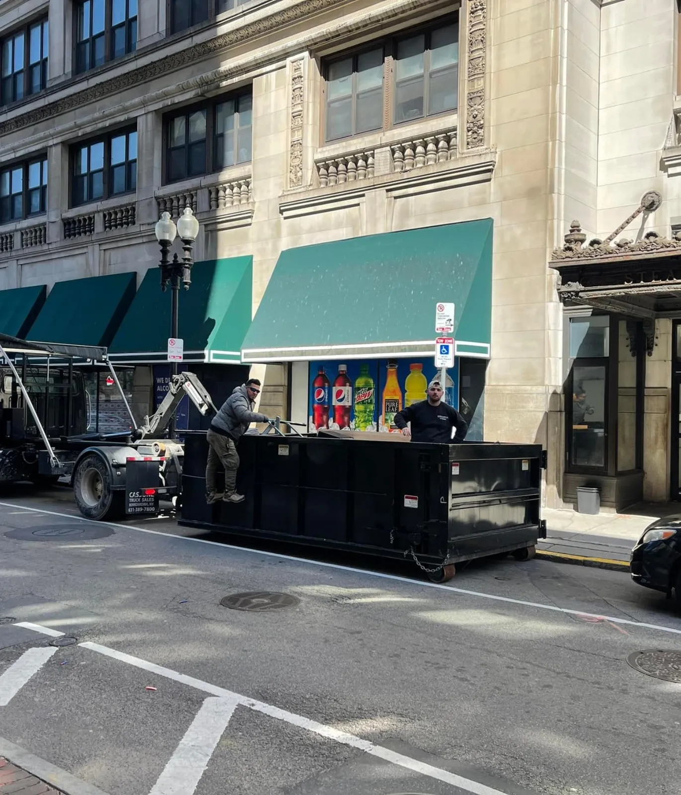 Workers in a Buddy & Son Cleanouts rental dumpster