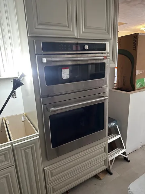 A stainless wall oven and microwave combo wired and set into the cabinet run during a kitchen remodel.