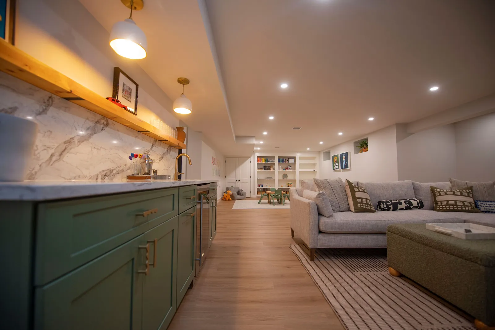 Custom Basement Remodeling project features overhead lighting, wet bar, wood floors, and tons of built-in cabinets.