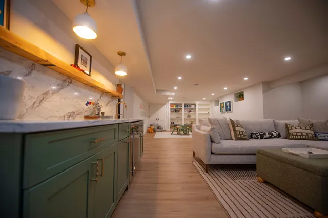 Custom Basement Remodeling project features overhead lighting, wet bar, wood floors, and tons of built-in cabinets.
