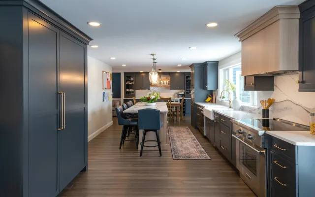 Modern kitchen with blue island, dark cabinets, wood flooring, and dining area by bright windows