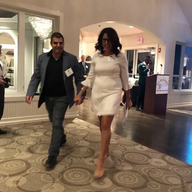 A woman in a white dress is walking with a man in a suit