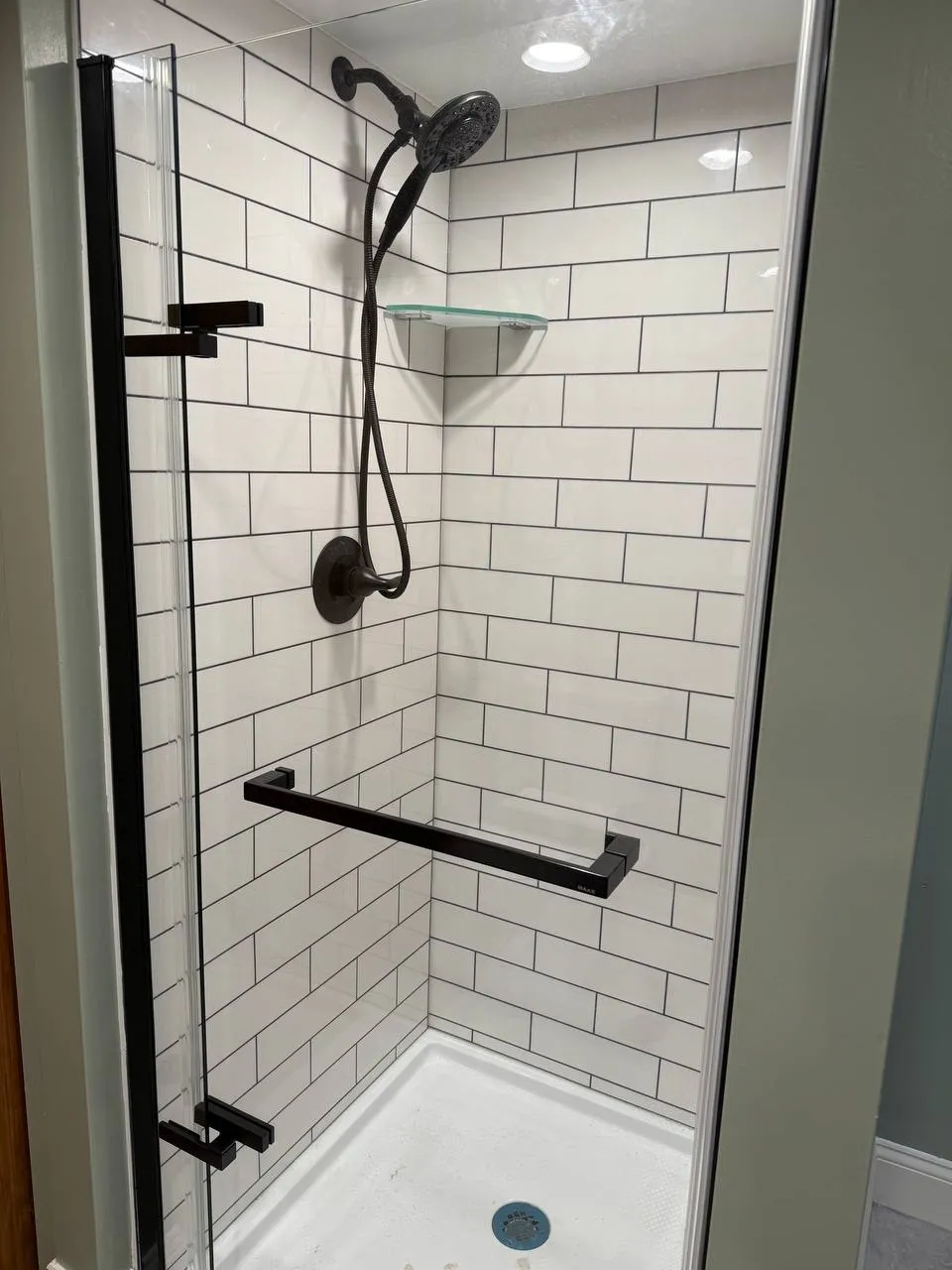 Walk-in shower with white subway tile, matte black fixtures and grab bar