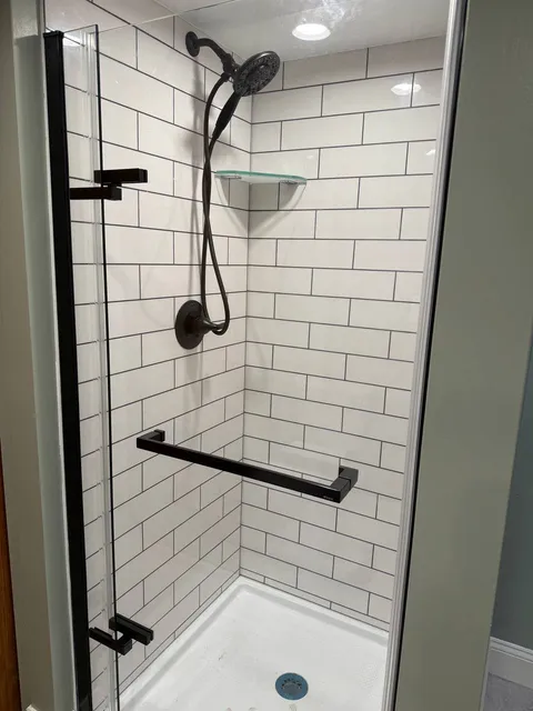 Walk-in shower with white subway tile, matte black fixtures and grab bar