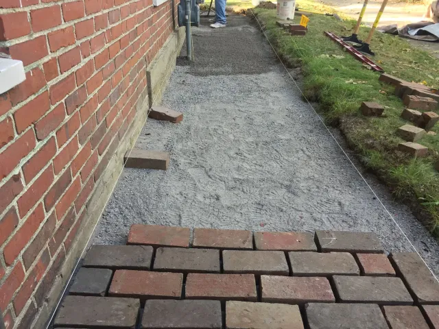 Brick walkway under construction next to a brick building.