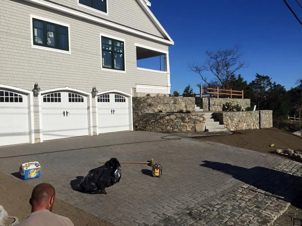 Cobblestone-bordered paver driveway with stone retaining walls