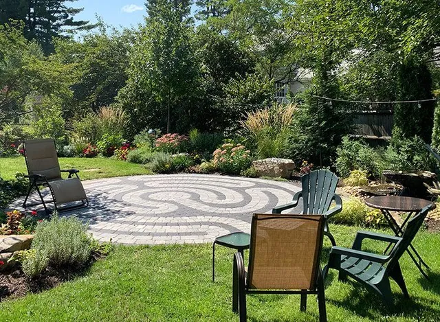 There is a labyrinth in the middle of the garden surrounded by chairs and tables.