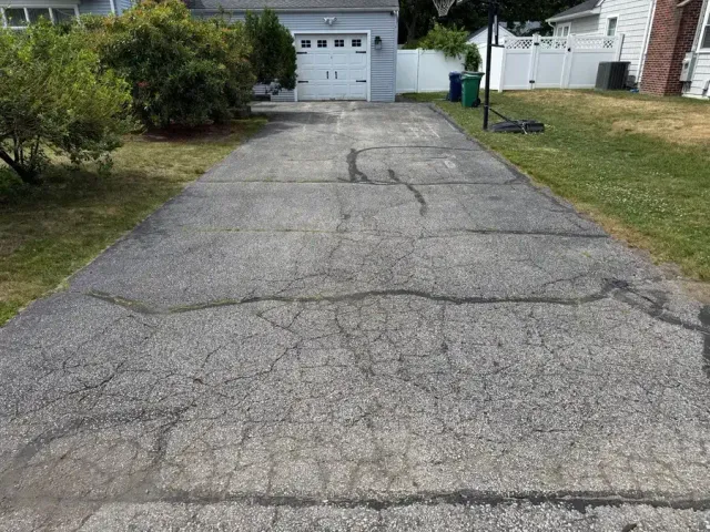 Cracked and deteriorated asphalt pavement showing freeze-thaw damage and UV oxidation