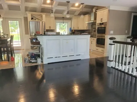 Open concept kitchen with white island, cabinets, and dark wood flooring